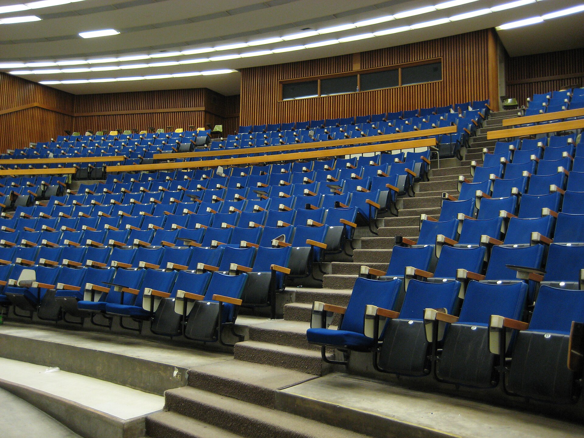 Un amphithéâtre universitaire vide, rangées de sièges bleus — passer un examen blanc du TCF Canada en conditions réelles