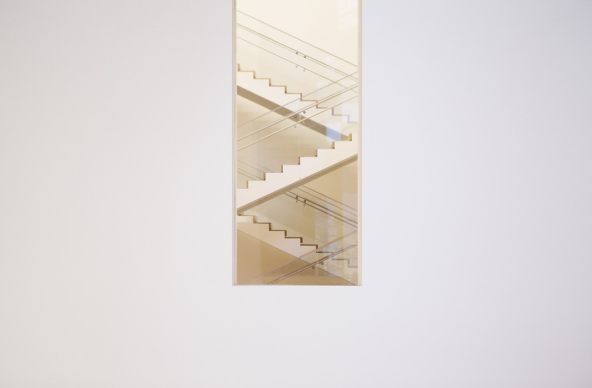 Un escalier blanc aperçu par une ouverture dans un mur clair — franchir le palier entre B1 et B2 en français
