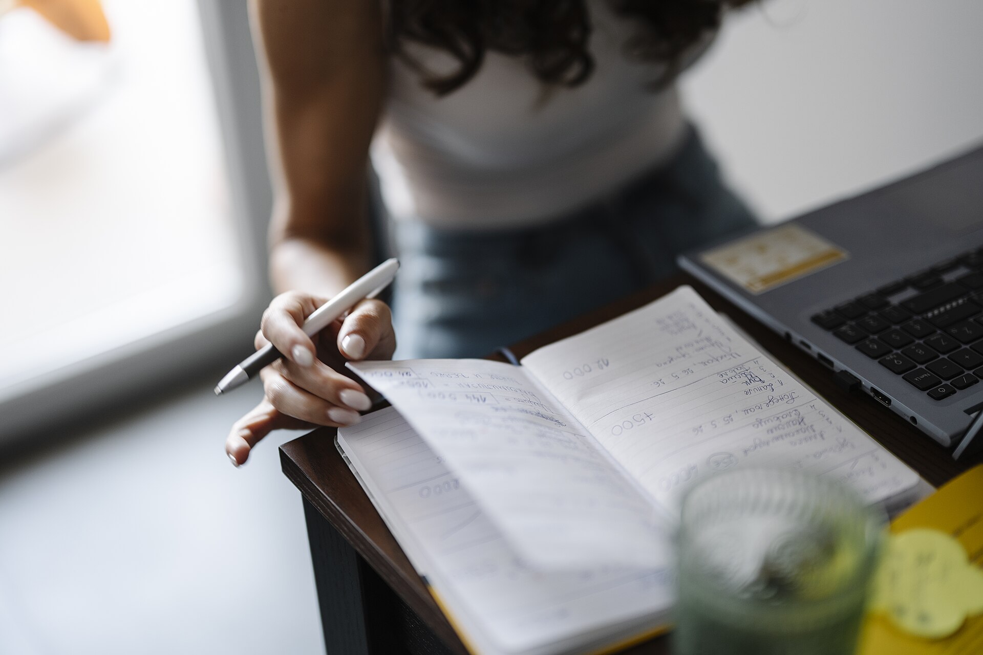 Personne qui relit ses notes dans un carnet, devant un ordinateur portable — préparation au TCF Canada