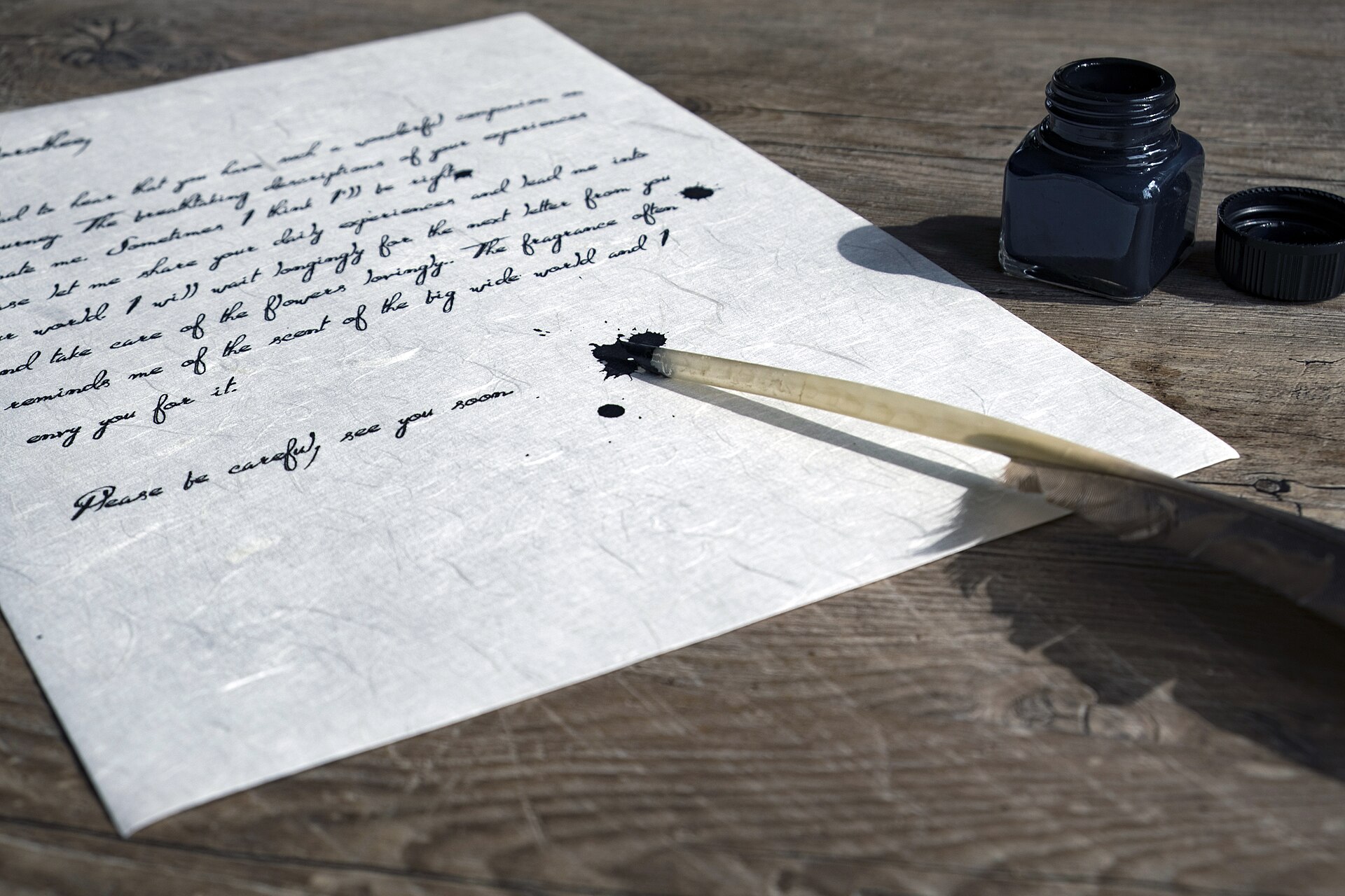 Lettre manuscrite posée sur une table en bois, avec une plume et un encrier